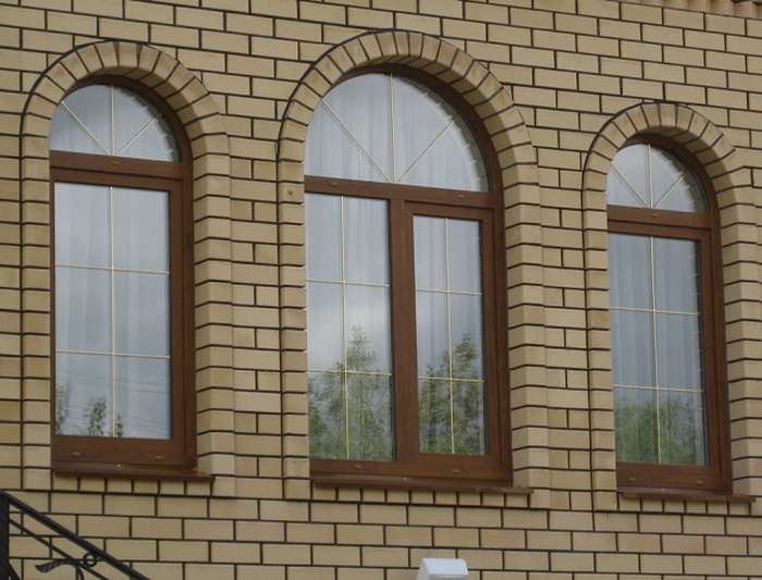 Остекление фасада дома арочными коричневыми окнами